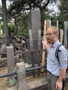 Photo of Dr. Justin Stein with a tour group at the Usui memorial stone in Tokyo