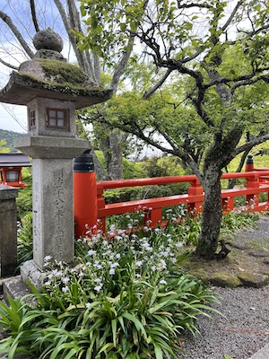 Photo of a stone lantern and red fence on a terrace of the main temple at Mount Kurama.